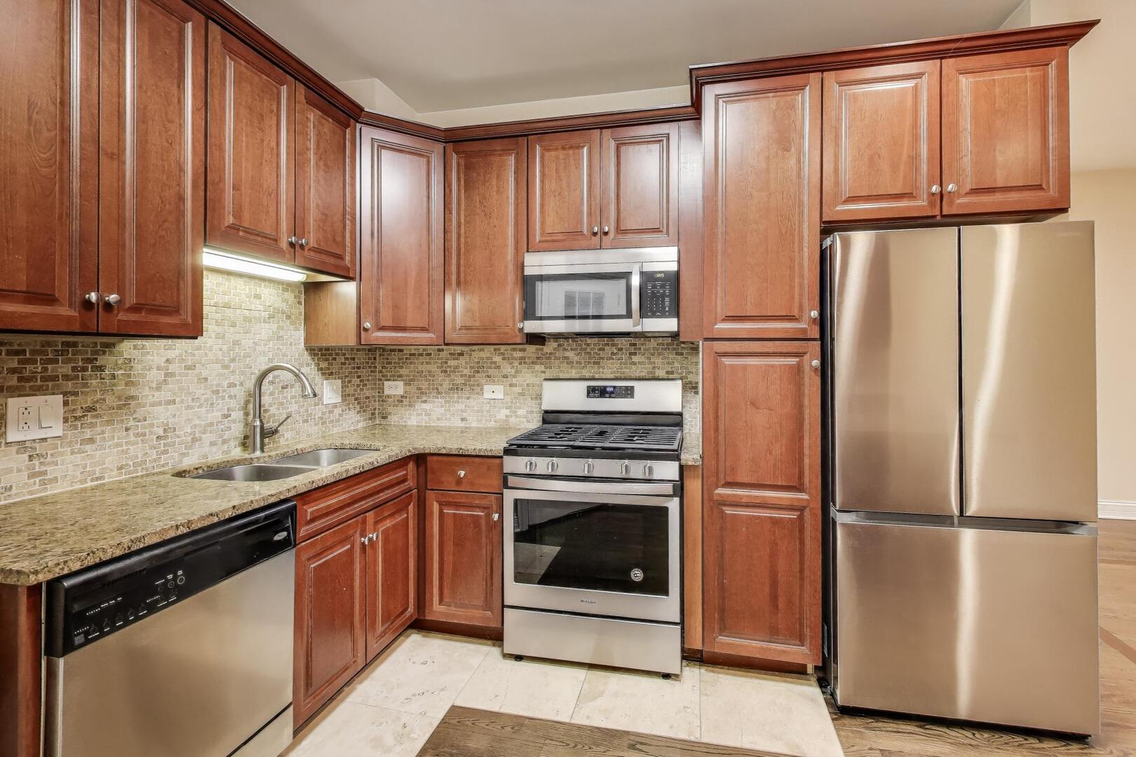 4432 North Dover Street, Unit 1S Chicago, IL 60640 - Photo 8 of 30 a kitchen with granite countertop wooden cabinets and stainless steel appliances