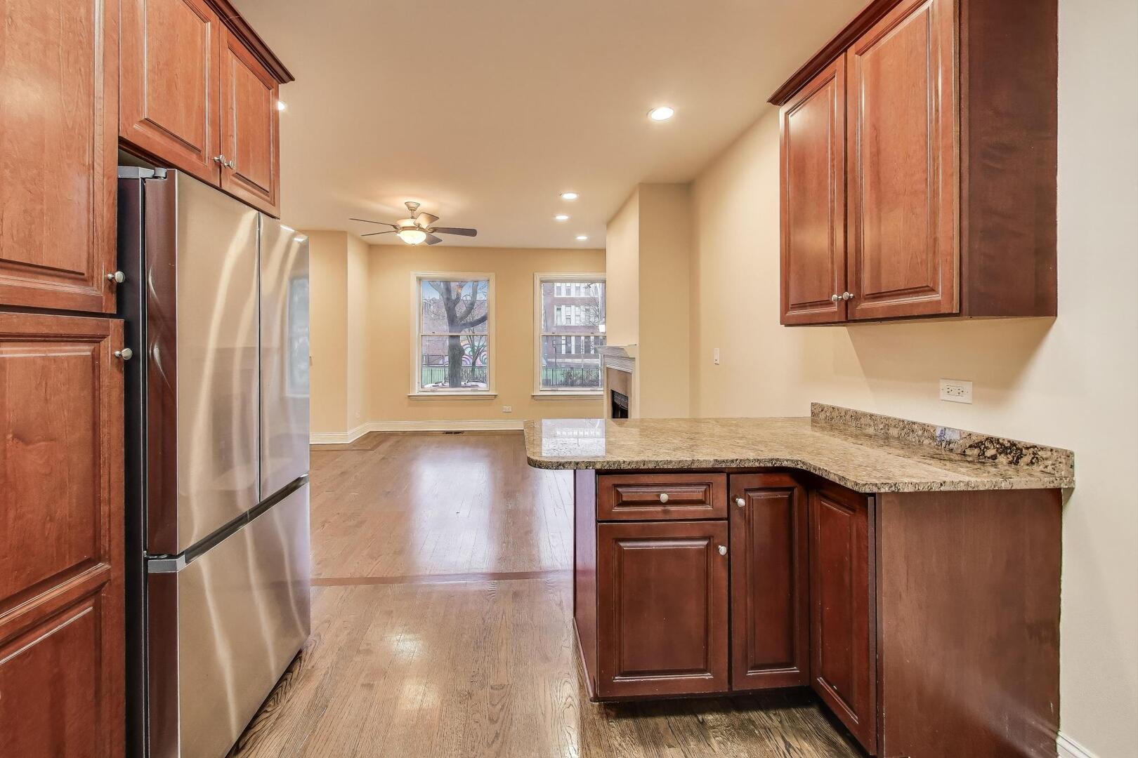 4432 North Dover Street, Unit 1S Chicago, IL 60640 - Photo 9 of 30 a kitchen with stainless steel appliances granite countertop a refrigerator a sink and wooden cabinets