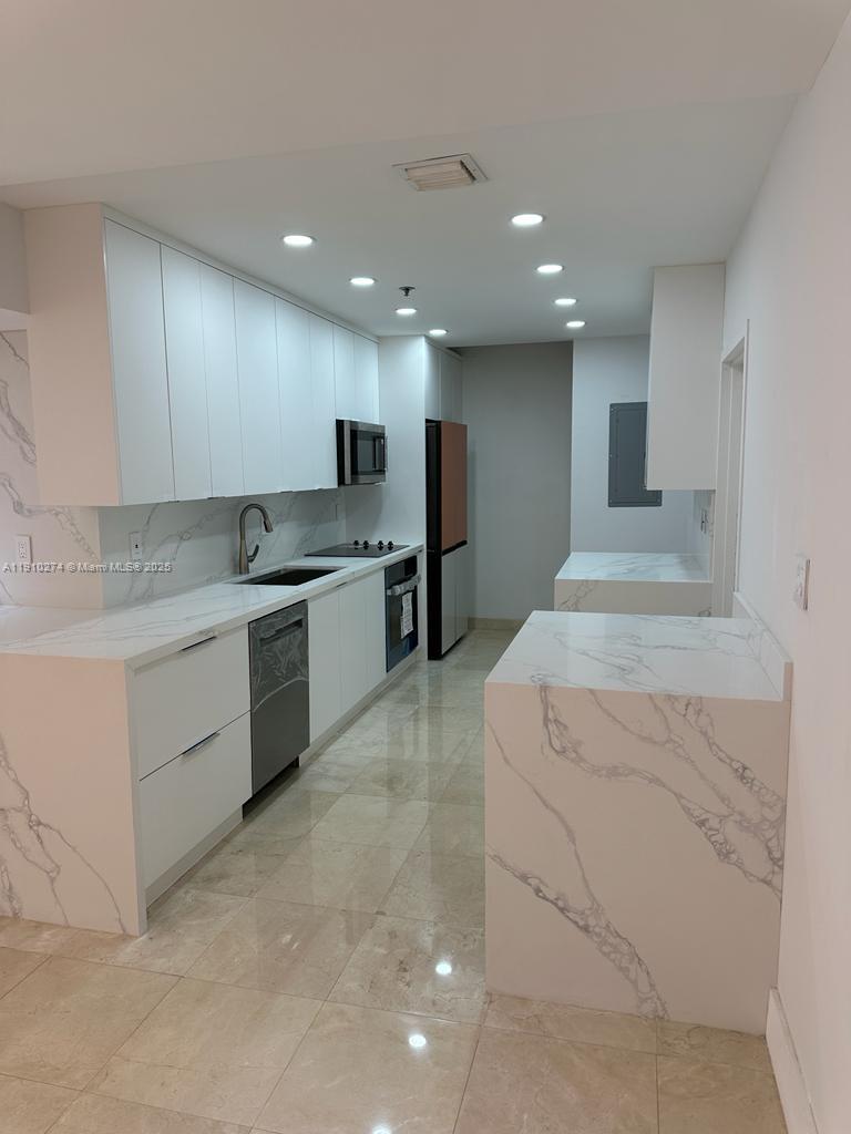 251 Crandon Boulevard, Unit 430 Key Biscayne, FL 33149 - Photo 6 of 19 a large kitchen with stainless steel appliances granite countertop a sink a stove and a refrigerator