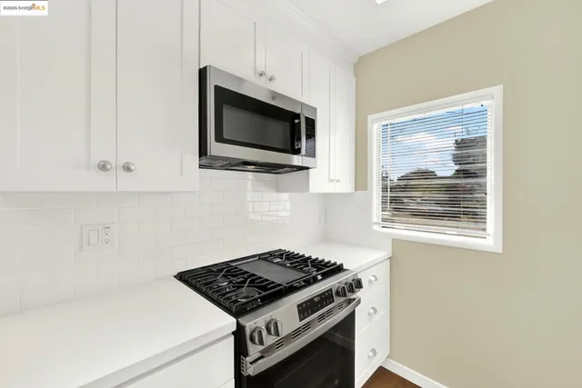 a kitchen with white cabinets and appliances