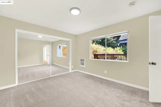 an empty room with windows fireplace and wooden floor