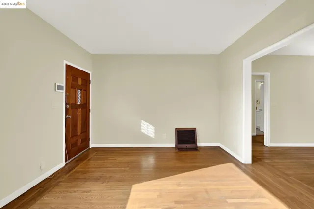 a view of a kitchen and an empty room with wooden floor and a window
