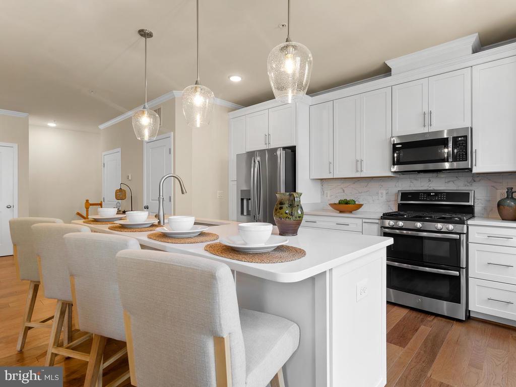 a kitchen with stainless steel appliances kitchen island a sink a stove a table and chairs