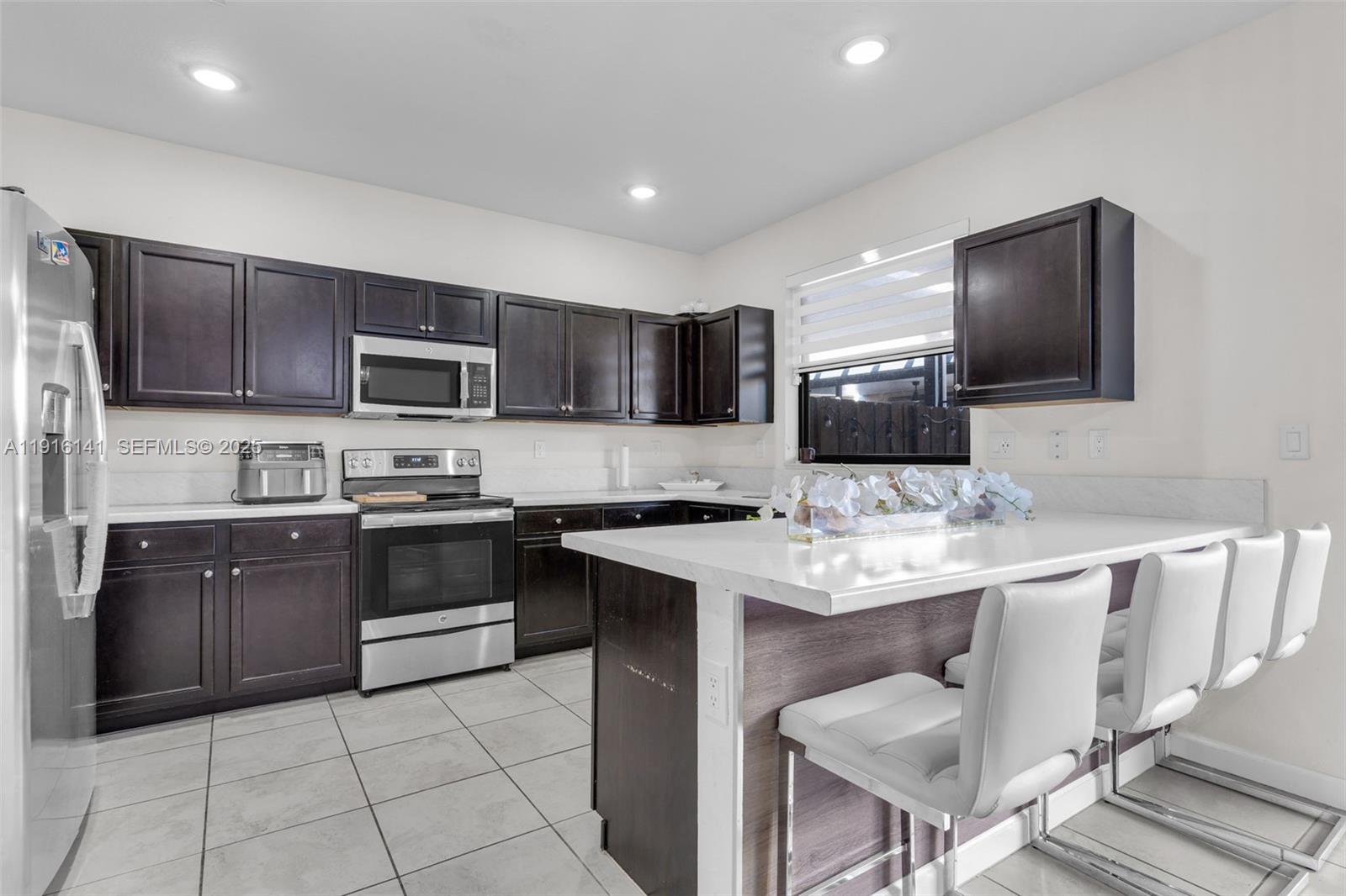 11413 Southwest 252nd Terrace Homestead, FL 33032 - Photo 12 of 40 a kitchen with a sink a stove a microwave a counter top space and cabinets