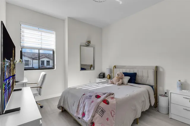 a bedroom with a large bed and a flat tv screen on dresser