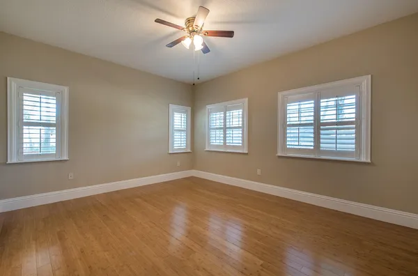 a view of empty room with wooden floor and fan