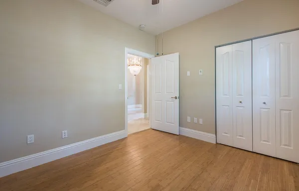 a view of an empty room with wooden floor and closet