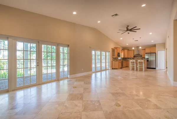 a view of an empty room with a kitchen view and a window