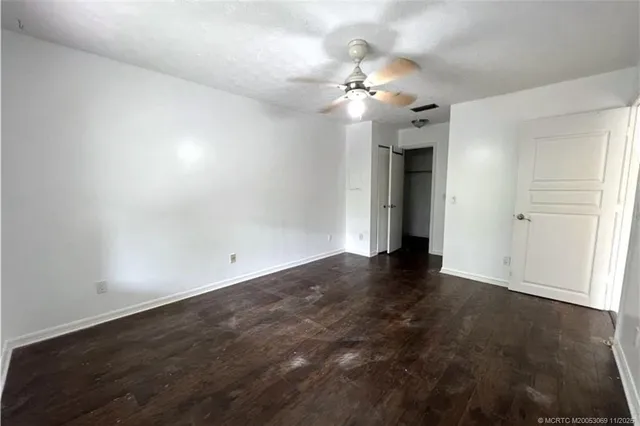 an empty room with wooden floor and chandelier fan
