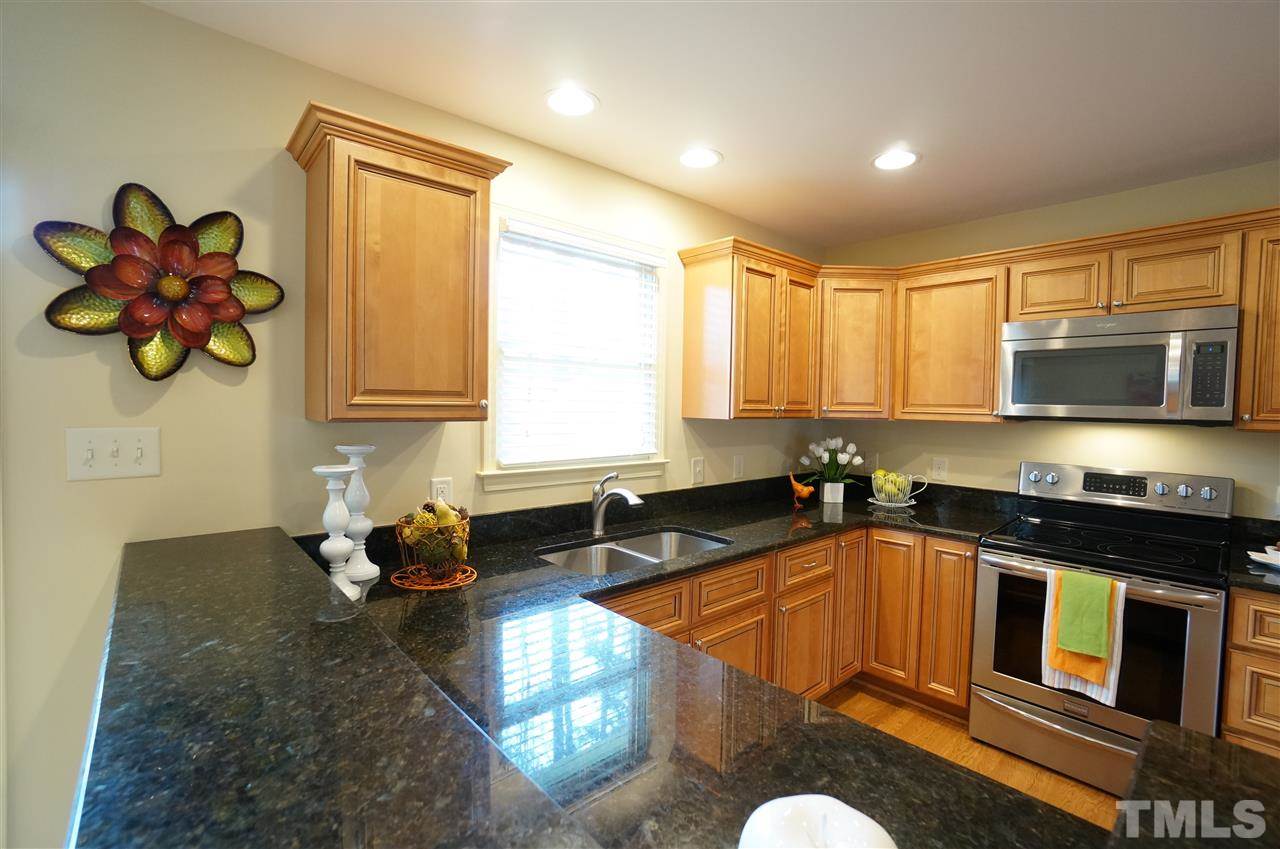 3413 Gemini Drive Raleigh, NC 27604 - Photo 6 of 16 a kitchen with stainless steel appliances granite countertop a sink a stove a microwave a counter space and cabinets