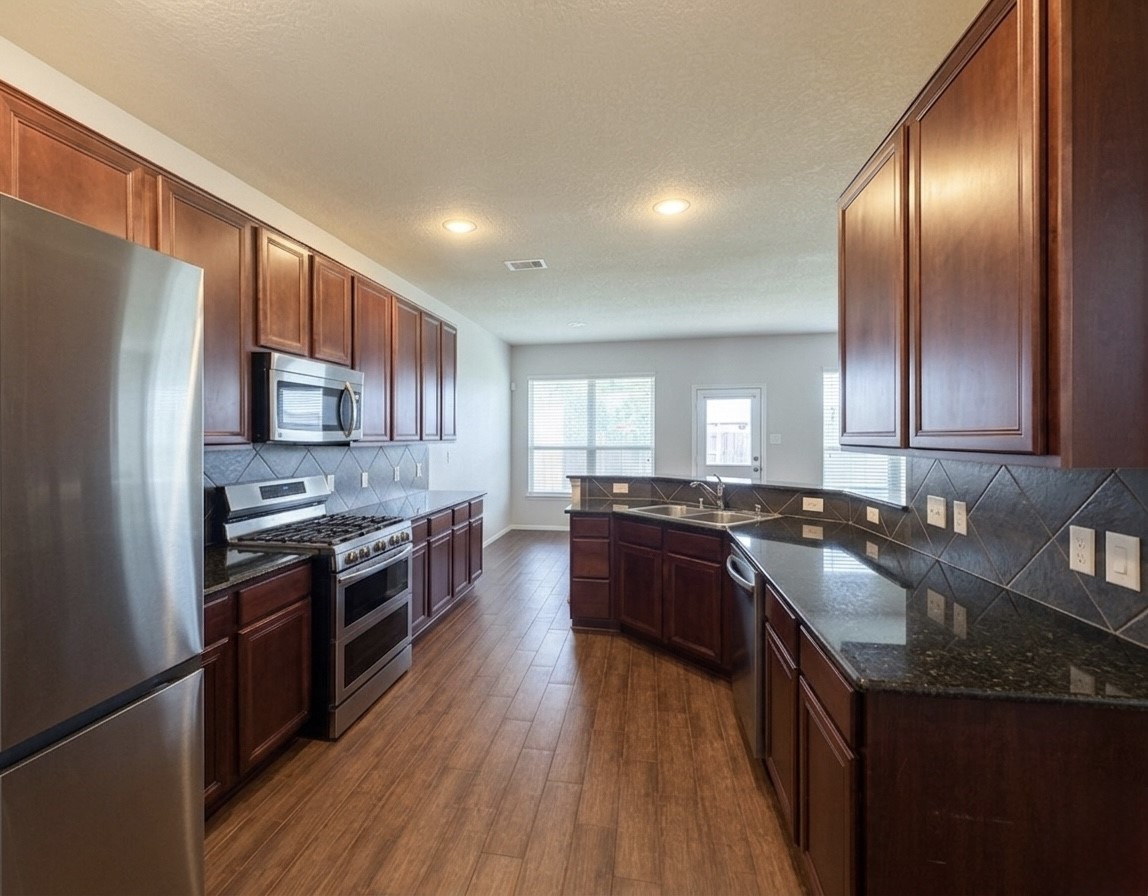 9908 Climbing Tree Street Conroe, TX 77385 - Photo 5 of 26 a kitchen with stainless steel appliances granite countertop a stove a sink dishwasher a refrigerator and a oven