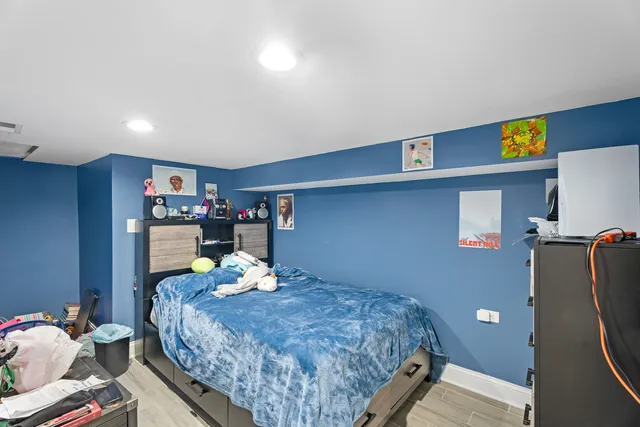 a bedroom with a bed and a potted plant on the dresser