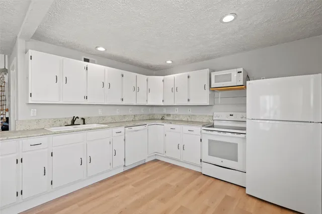 a kitchen with granite countertop white cabinets and white appliances