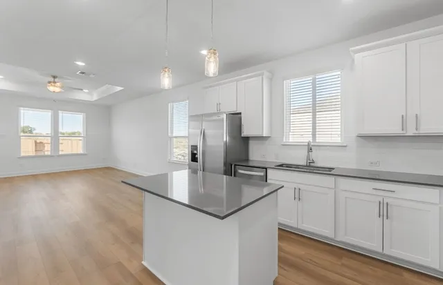 a kitchen with stainless steel appliances granite countertop white cabinets a refrigerator a sink a stove a microwave and island