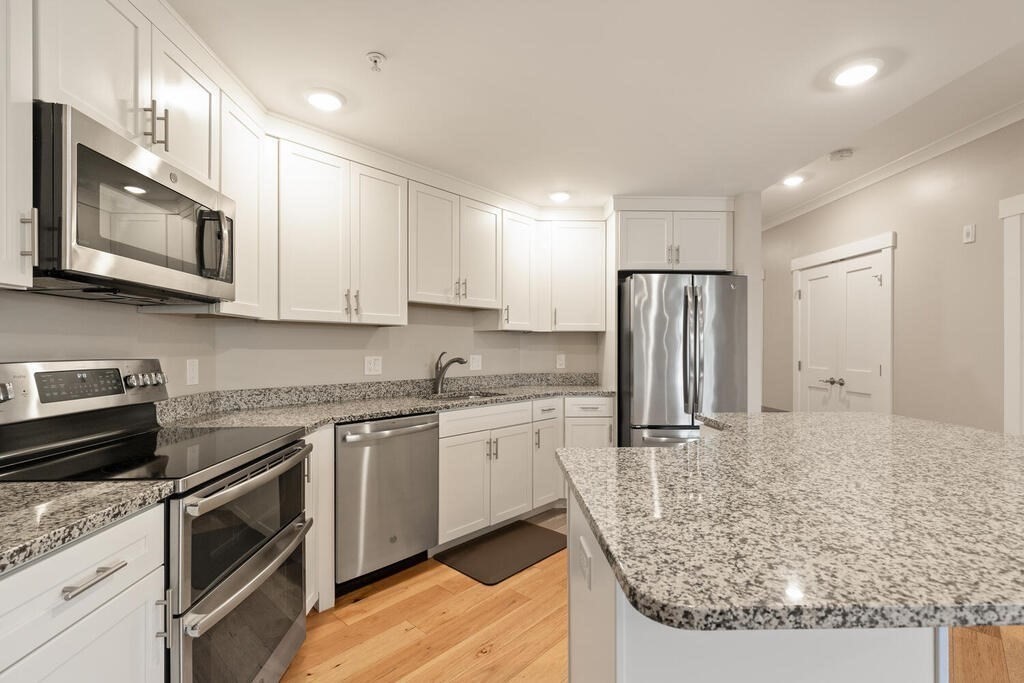 11 Executive Drive, Unit 118 Stoneham, MA 02180 - Photo 2 of 36 a kitchen with stainless steel appliances granite countertop a stove top oven a refrigerator a sink and dishwasher