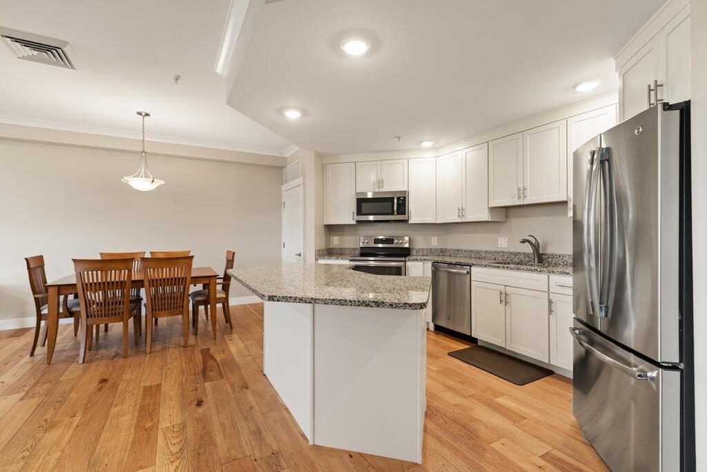 11 Executive Drive, Unit 118 Stoneham, MA 02180 - Photo 6 of 36 a kitchen with white cabinets and stainless steel appliances