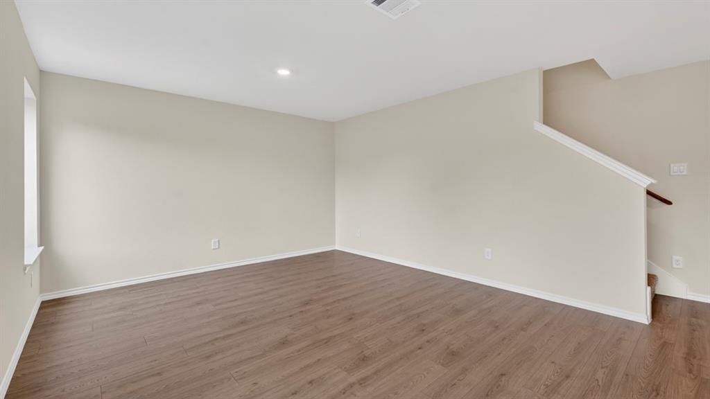 3534 Spring Time Street Forney, TX 75126 - Photo 5 of 24 Spacious room featuring wood-finish flooring, light neutral wall tones, white trim, recessed lighting, and a staircase with a white railing and wood handrail