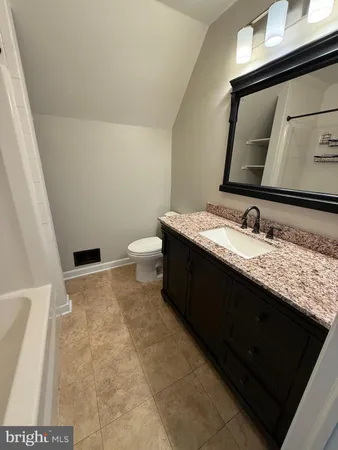 a bathroom with a granite countertop sink a toilet and a mirror