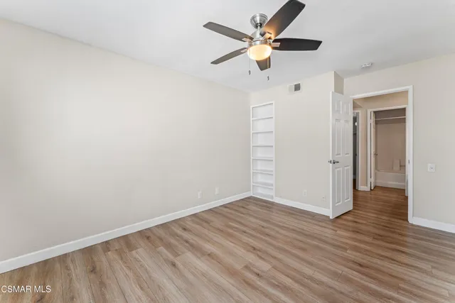 an empty room with wooden floor and a ceiling fan