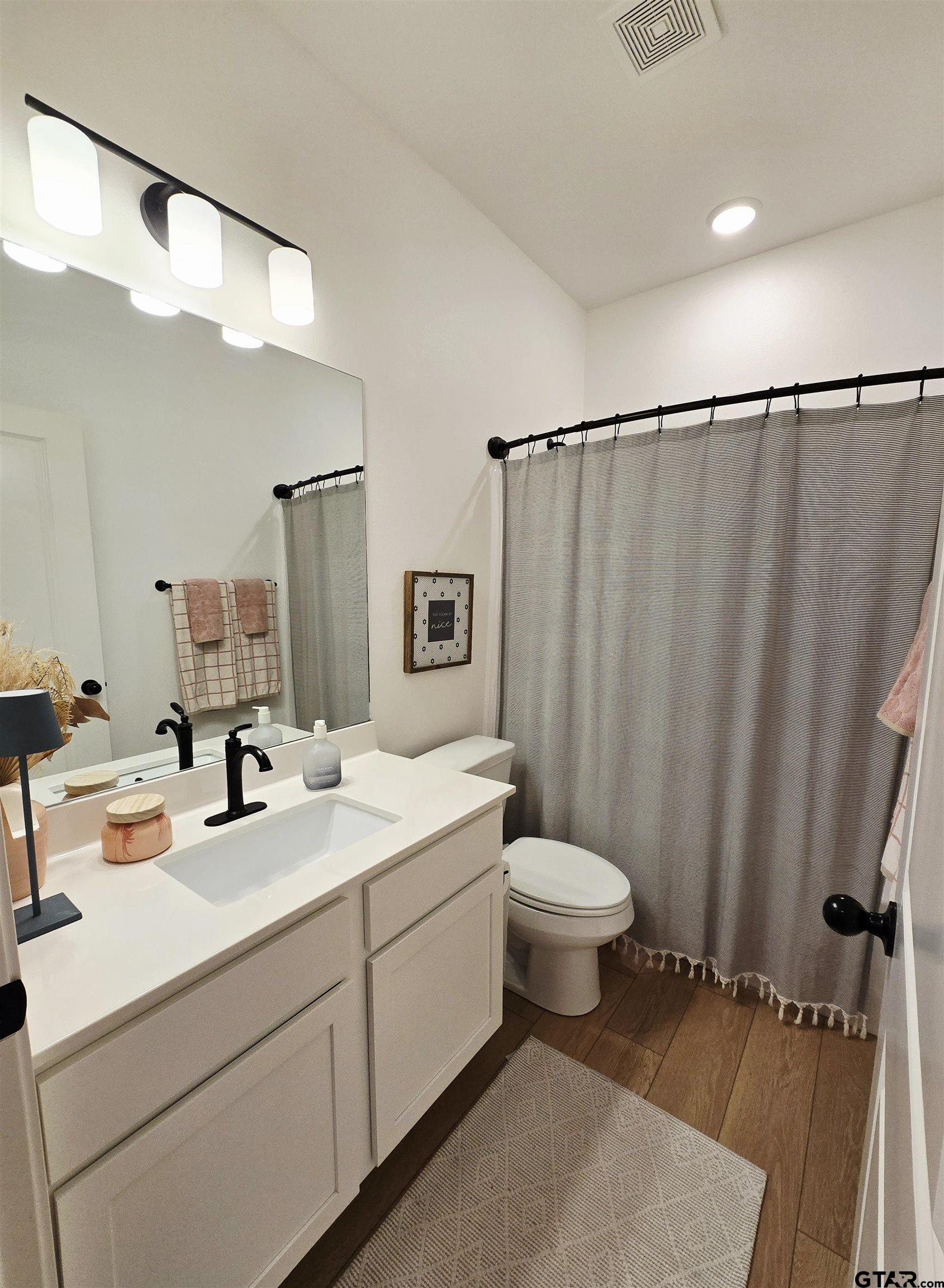 14932 Turtle Crk Rnch Road Flint, TX 75762 - Photo 8 of 33 a bathroom with a sink a toilet a mirror and shower curtain