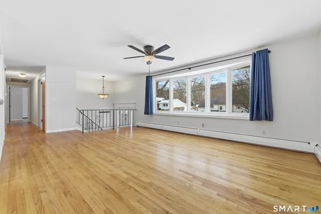 a view of an empty room with a window and wooden floor