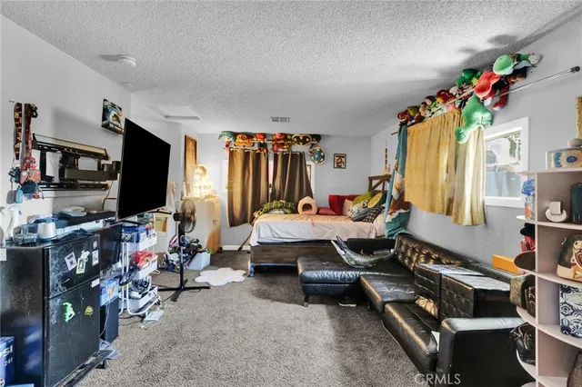 a living room with furniture a flat screen tv and a refrigerator