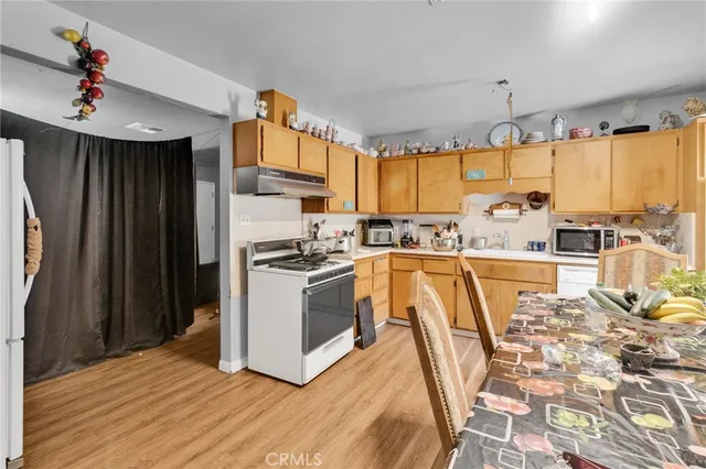 a kitchen with kitchen island granite countertop a stove a sink dishwasher and a refrigerator with wooden floor