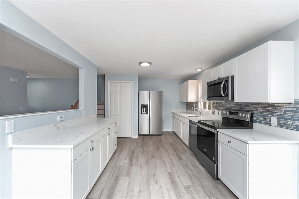 164 Sterling Road Lancaster, MA 01523 - Photo 6 of 36 a large kitchen with a center island wooden floor and stainless steel appliances