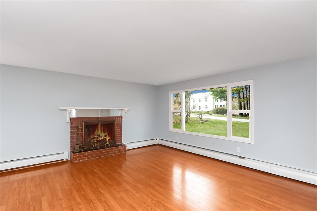 164 Sterling Road Lancaster, MA 01523 - Photo 10 of 36 an empty room with a fireplace and windows
