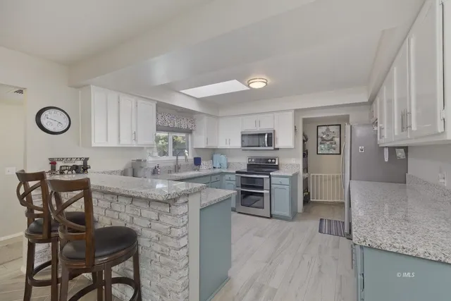 a kitchen with stainless steel appliances granite countertop a stove top oven a sink dishwasher and a refrigerator with wooden cabinets