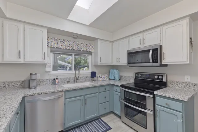 a kitchen with stainless steel appliances granite countertop a sink a stove a microwave and cabinets
