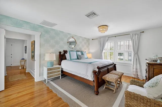 a bedroom with a bed wooden floor and view living room
