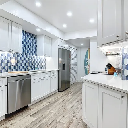 a kitchen with a sink dishwasher a refrigerator and cabinets with wooden floor
