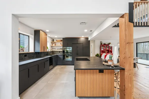 a kitchen with stainless steel appliances granite countertop a sink dishwasher and a refrigerator with wooden floor