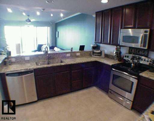 7070 Key Haven Road, Unit 603 Seminole, FL 33777 - Photo 1 of 1 a kitchen with stainless steel appliances granite countertop wooden cabinets a stove a sink and a oven