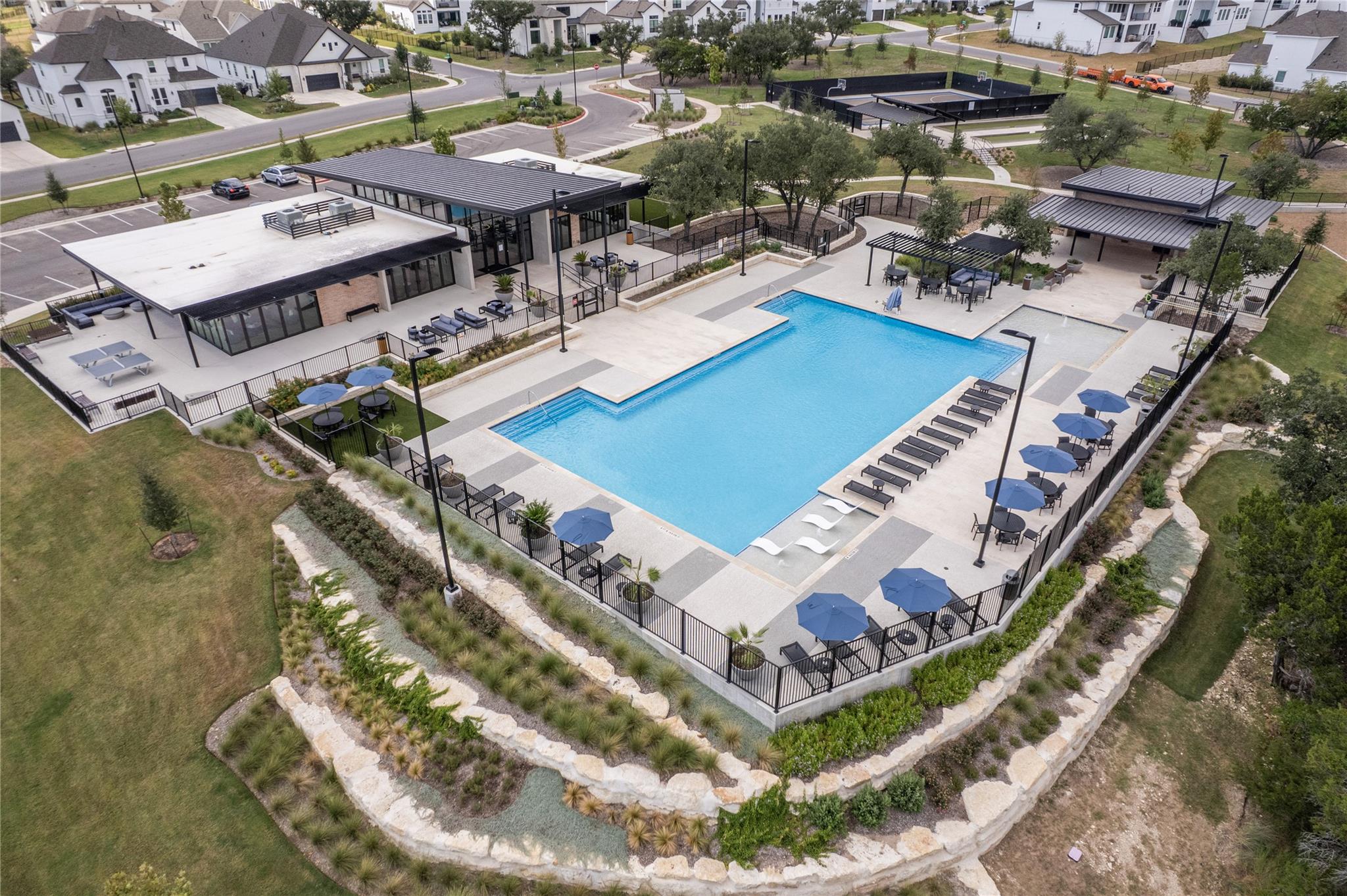 5009 Forenza Trace Leander, TX 78641 - Photo 36 of 39 a view of a swimming pool with lawn chairs and a dining table under an umbrella