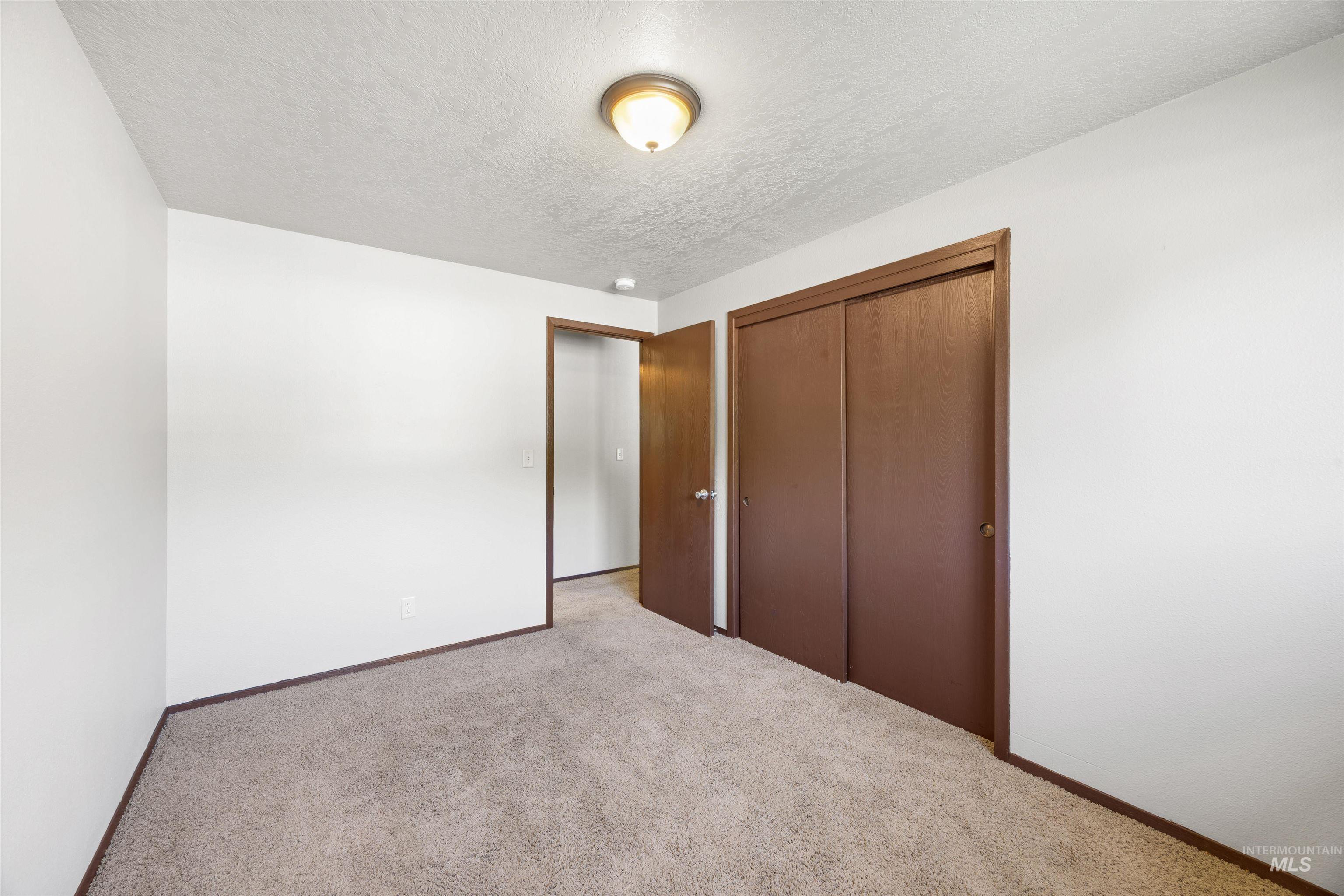 9 Villa Drive Middleton, ID 83644 - Photo 16 of 33 Neutral wall paint with textured ceiling, brown trim, brown sliding closet doors, and beige carpet flooring