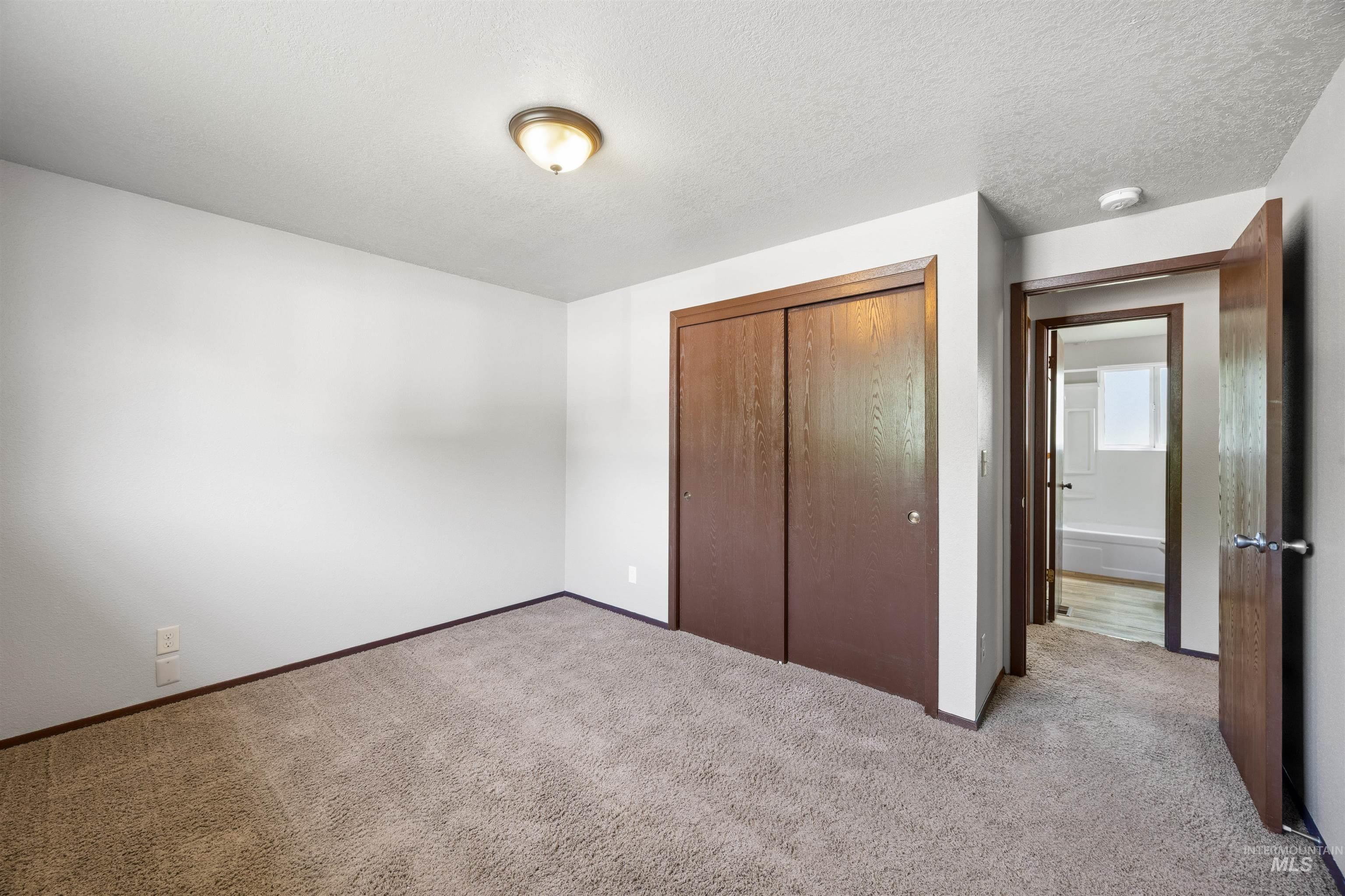 9 Villa Drive Middleton, ID 83644 - Photo 19 of 33 Carpeted bedroom featuring a ceiling-mounted light fixture, white walls, and a wood-finish bi-fold closet