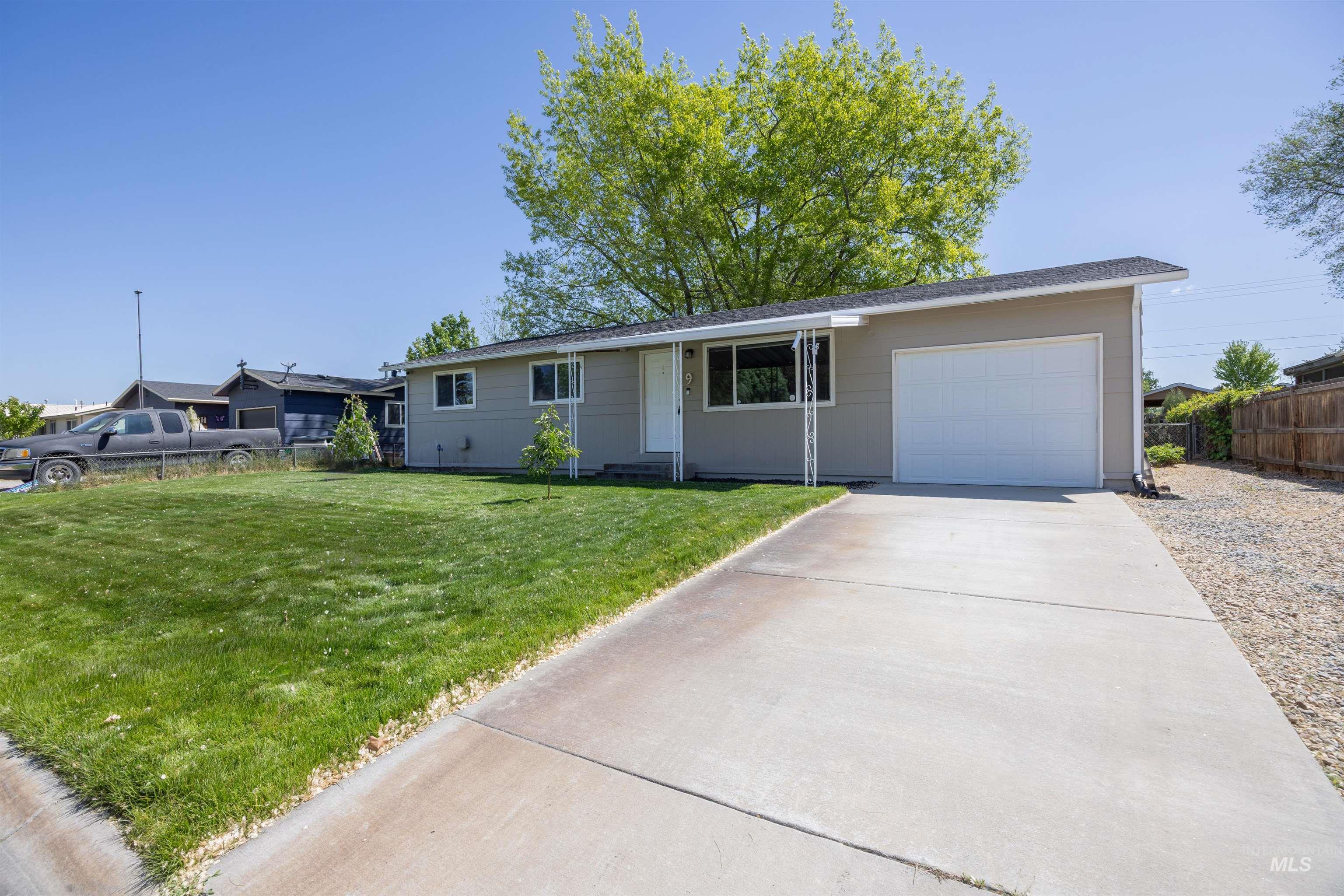 9 Villa Drive Middleton, ID 83644 - Photo 4 of 33 Your new home features a neutral-toned exterior, an attached garage with a white door, a concrete driveway, a front lawn with mature greenery, and a gravel side yard