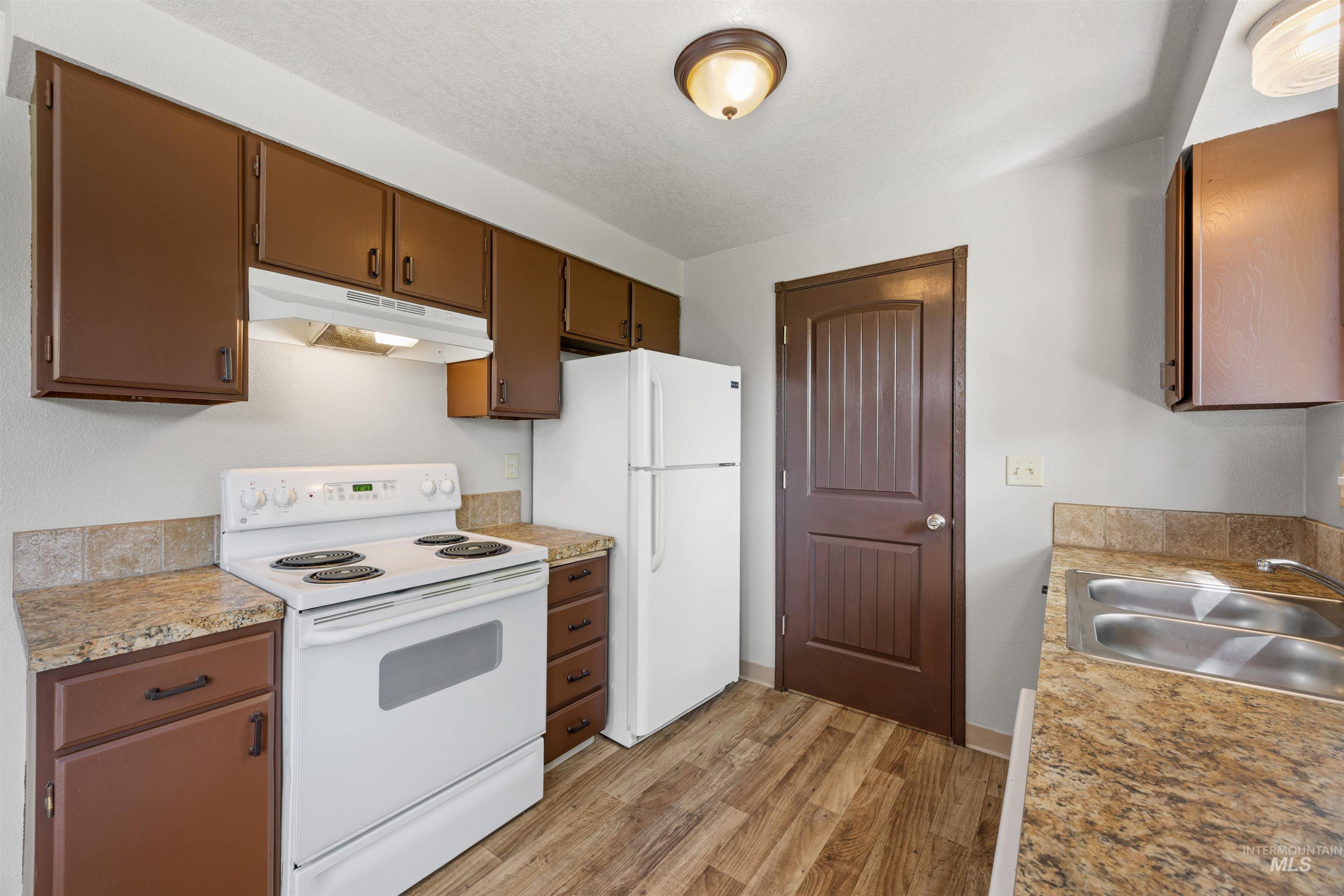 9 Villa Drive Middleton, ID 83644 - Photo 6 of 33 Kitchen featuring wood-finish flooring, brown cabinetry, and light-colored countertops with a matching backsplash