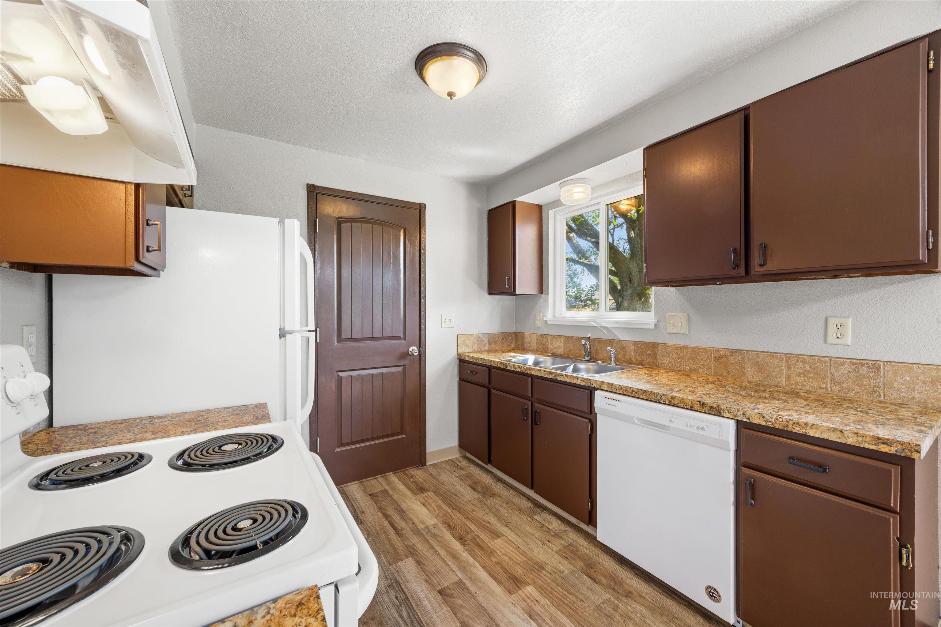 9 Villa Drive Middleton, ID 83644 - Photo 7 of 33 Kitchen featuring dark wood-finish cabinetry, wood-finish flooring, and a window above the double-basin sink
