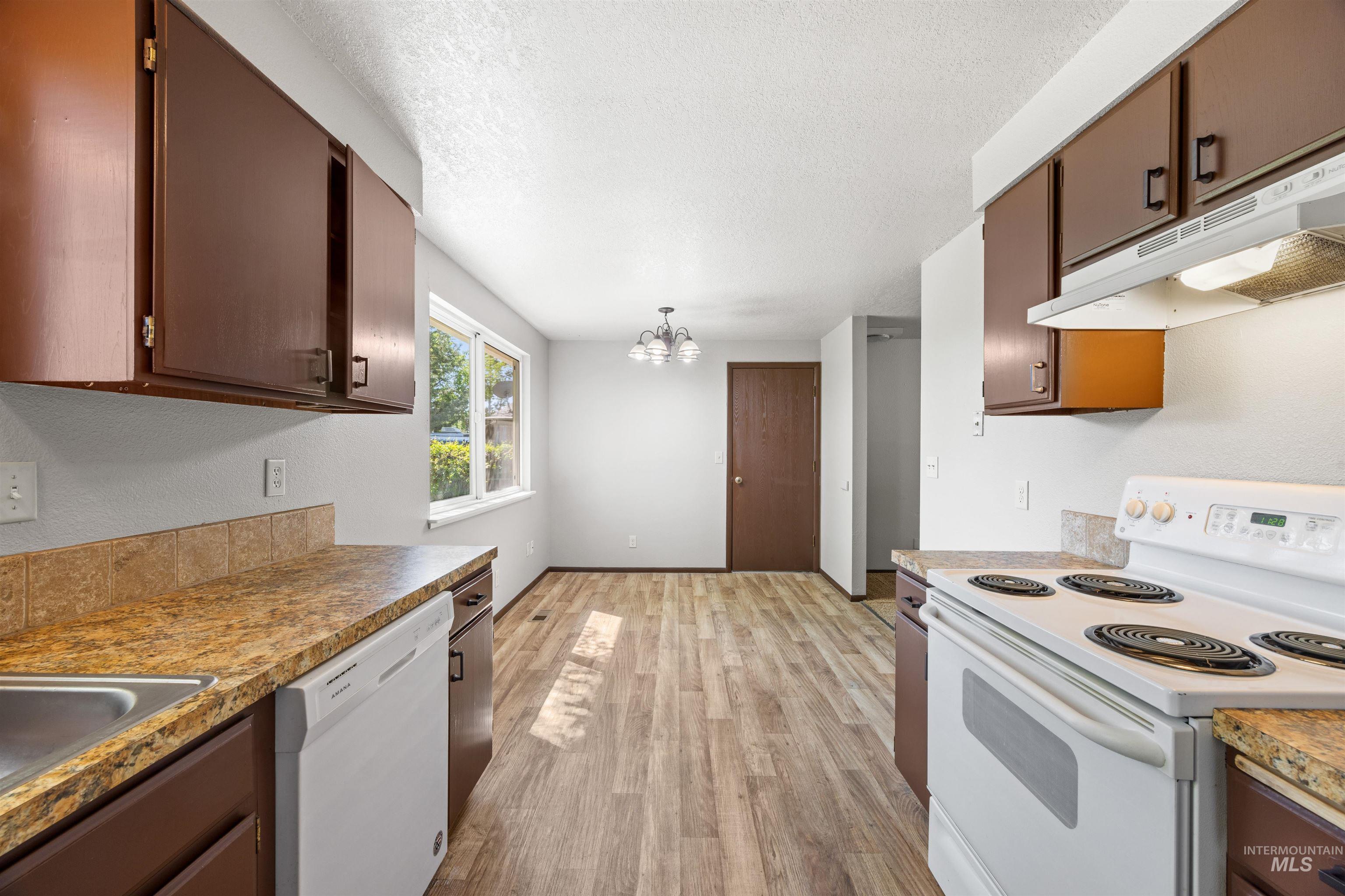 9 Villa Drive Middleton, ID 83644 - Photo 8 of 33 Kitchen and dining area featuring wood-finish flooring, brown cabinetry, and light countertops