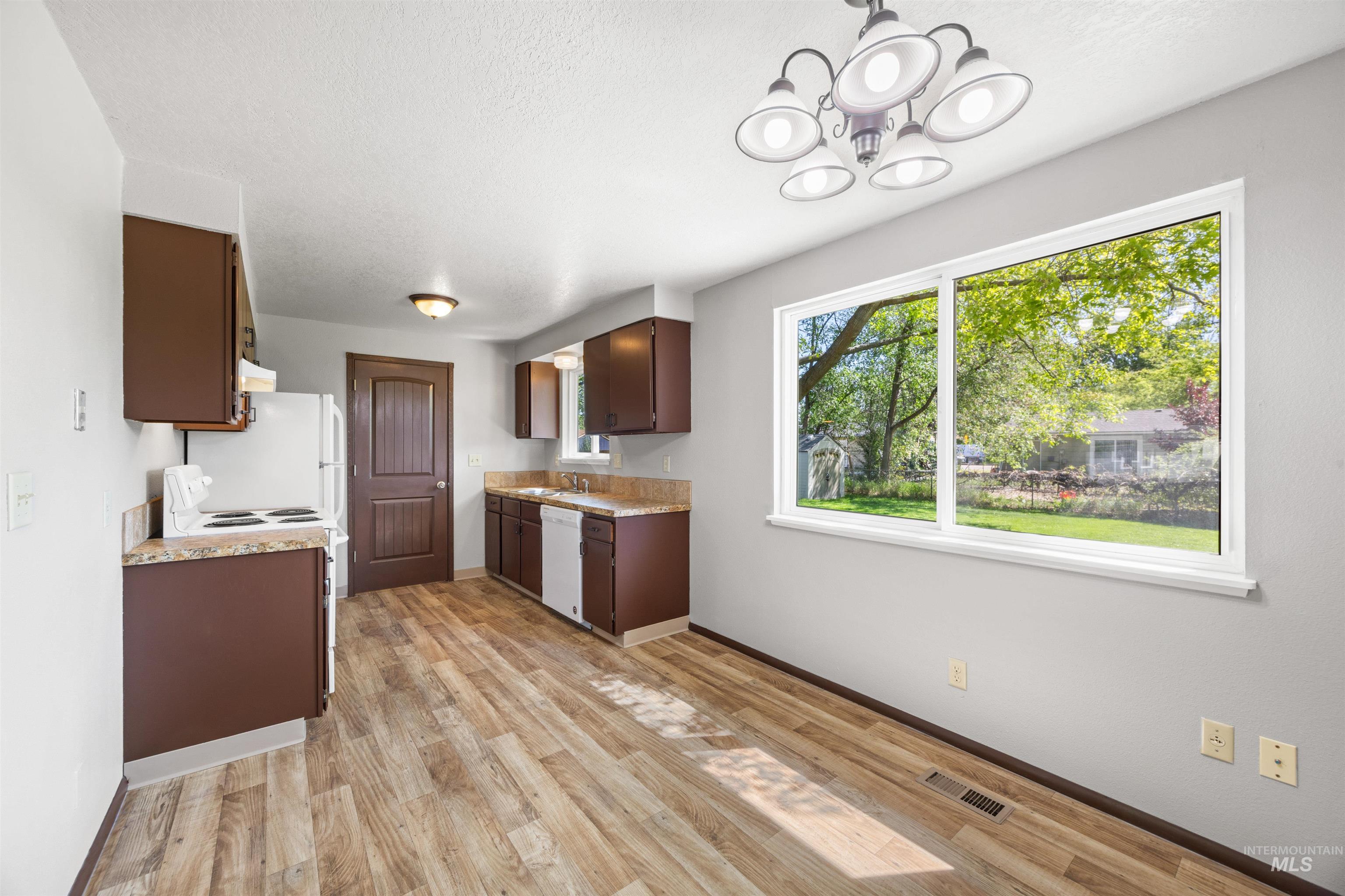 9 Villa Drive Middleton, ID 83644 - Photo 9 of 33 Kitchen and dining area featuring wood-finish flooring, brown cabinetry, and light-toned countertops