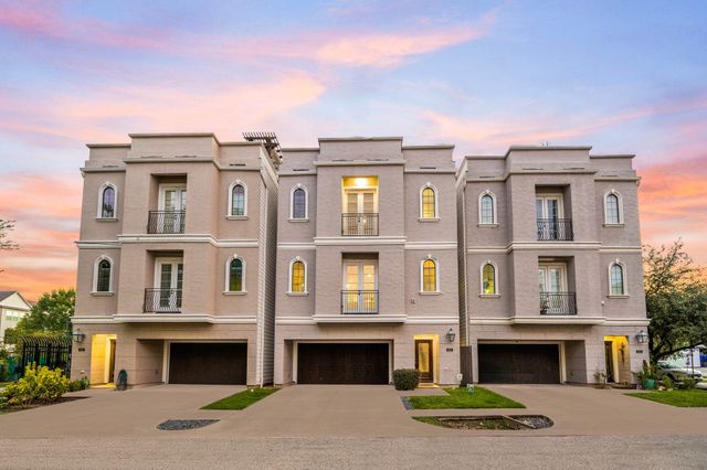 a front view of a multi story residential apartment building with yard and parking