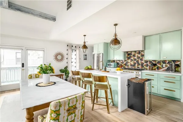 a kitchen with stainless steel appliances kitchen island granite countertop a table chairs and white cabinets
