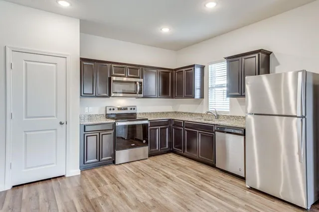 a kitchen with stainless steel appliances granite countertop a refrigerator stove and sink