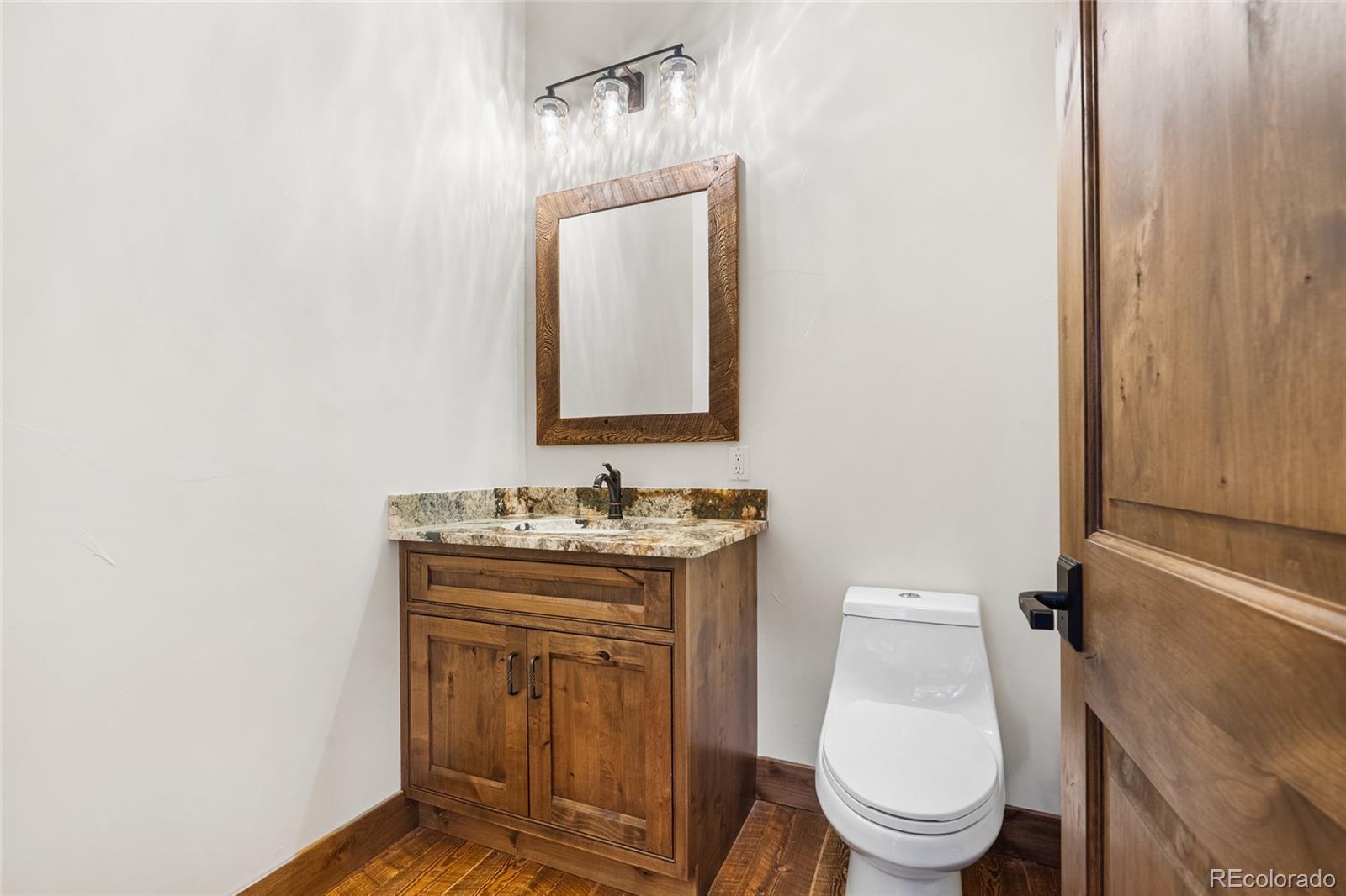 280 Double Tree Road Bailey, CO 80421 - Photo 19 of 43 a bathroom with a granite countertop toilet a mirror and a sink