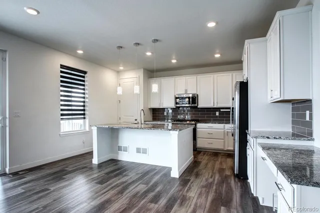 a kitchen with stainless steel appliances granite countertop a lot of counter space and wooden floors