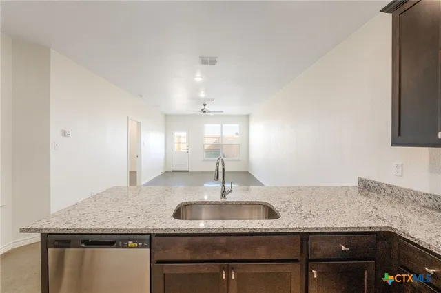 a kitchen with granite countertop a sink and refrigerator
