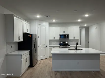 a kitchen with kitchen island white cabinets stainless steel appliances and sink